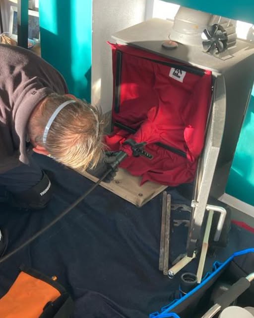 Greg sweeping a stove with protective sheeting and sweeping equipment in place